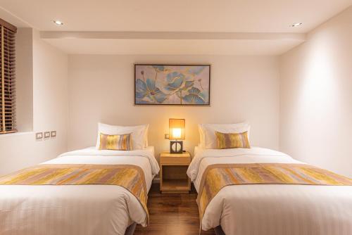 a room with two beds and a table with a lamp at Summit Windmill Golf Suite Hotel at Suvarnabhumi in Bangna