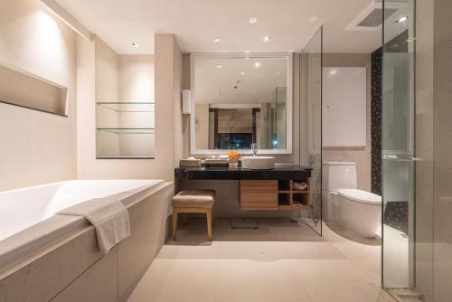 a bathroom with a tub and a sink and a toilet at Summit Windmill Golf Suite Hotel at Suvarnabhumi in Bangna
