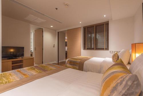 a hotel room with two beds and a flat screen tv at Summit Windmill Golf Suite Hotel at Suvarnabhumi in Bangna