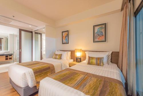 a hotel room with two beds and a window at Summit Windmill Golf Suite Hotel at Suvarnabhumi in Bangna