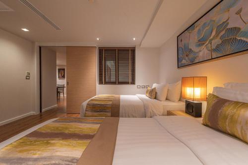 a hotel room with two beds and a tv at Summit Windmill Golf Suite Hotel at Suvarnabhumi in Bangna