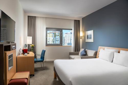 カイセリにあるノボテル カイセリのベッドとリビングルームが備わるホテルルームです。