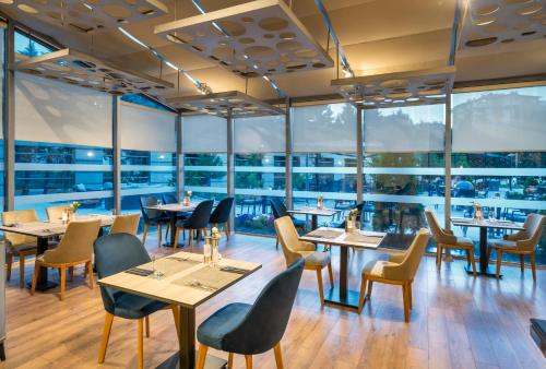 a restaurant with tables and chairs and large windows at Novotel Kayseri in Kayseri