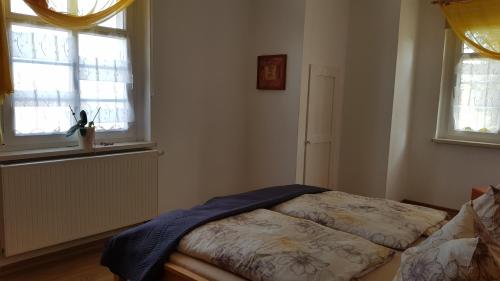 a small bedroom with a bed and two windows at FEWO Lichtblick in Bautzen