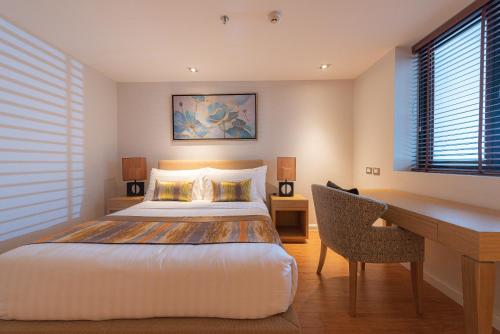 a bedroom with a bed and a desk and a desk at Summit Windmill Golf Suite Hotel at Suvarnabhumi in Bangna