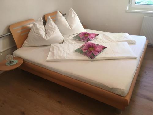 a bed with white pillows and pink flowers on it at Ferienwohnung Kohlweis in Döbriach