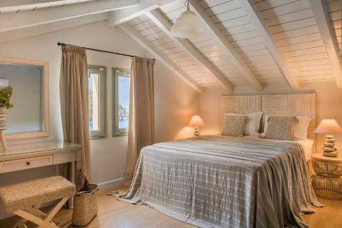 a bedroom with a bed and a desk and windows at Braunis Horio Villas in Asos