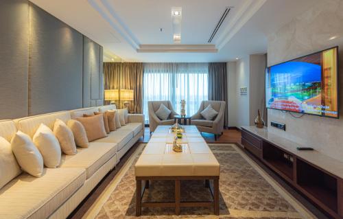 a living room with a large couch and a tv at Summit Windmill Golf Suite Hotel at Suvarnabhumi in Bangna