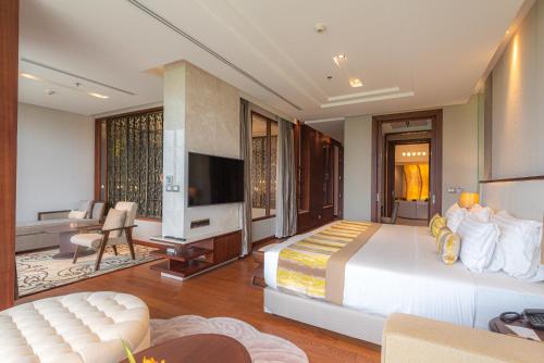 a hotel room with a large bed and a television at Summit Windmill Golf Suite Hotel at Suvarnabhumi in Bangna