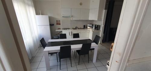 une cuisine avec une table, des chaises et un réfrigérateur dans l'établissement grand studio malo les bains - dunkerque, à Dunkerque