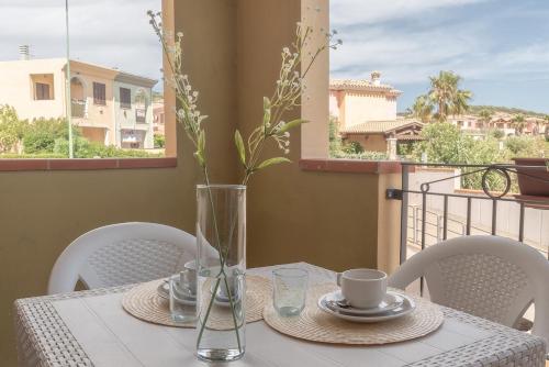 uma mesa com cadeiras e um vaso com flores em Apartments in residence with swimming pool in Villasimius em Villasimius