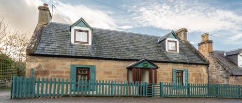 an old stone house with a fence in front of it at Luxury Cottage with Mountain View’s in Cononbridge