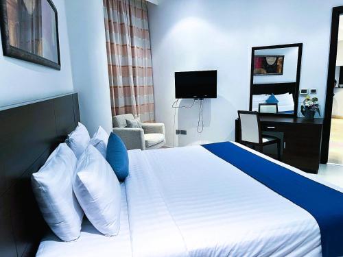 a hotel room with a bed with blue and white pillows at Butterfly Residence in Manama