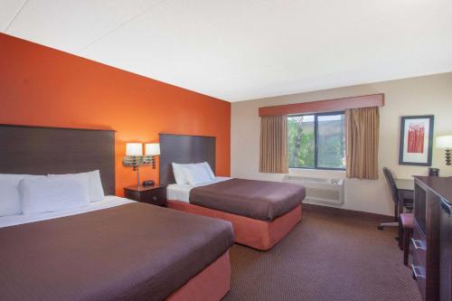 a hotel room with two beds and a desk at AmericInn by Wyndham Ham Lake in Ham Lake