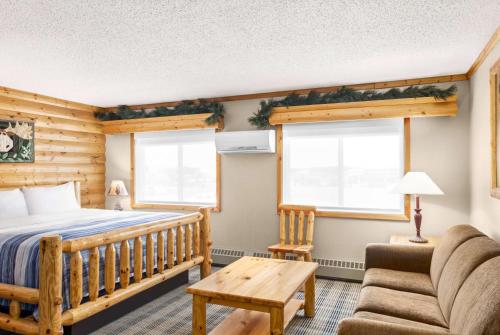 a bedroom with a bed and a couch at AmericInn by Wyndham Roseau in Roseau