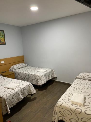 a room with three beds in a room at Hostal Tres Hermanos in Getafe