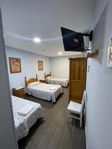 a room with two beds and a flat screen tv at Hostal Tres Hermanos in Getafe