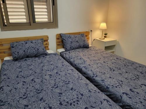 a bedroom with two beds with blue covers and a window at Home away from home in Safed