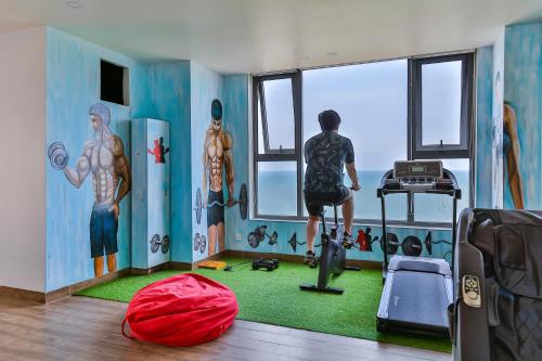 a room with a man standing on a treadmill looking out the window at Azura Gold Hotel & Apartment in Nha Trang