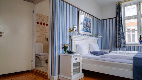 a bedroom with a king sized bed and a toilet at Hotel Ærø in Svendborg