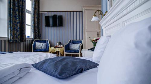 a bedroom with a white bed and two blue chairs at Hotel Ærø in Svendborg