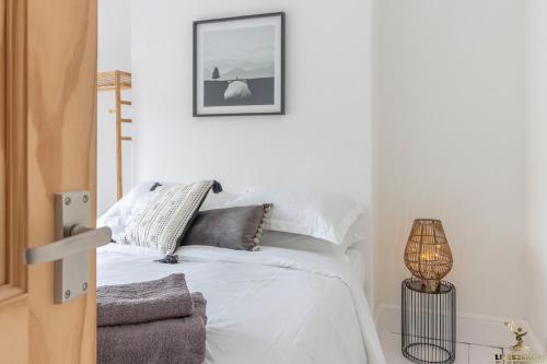 1 dormitorio con 1 cama con sábanas blancas y lámpara en Luxe Garden House for 6 in Central Exeter, en Exeter