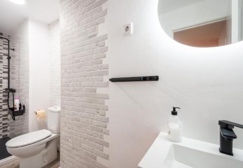bagno bianco con parete di mattoni bianchi di Apartamento Madrid Centro - Barrio de Las Letras a Madrid