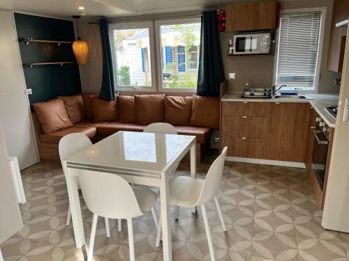 a kitchen and a living room with a table and chairs at Mobil home 6/8 personnes aux Mathes / La Palmyre in Les Mathes