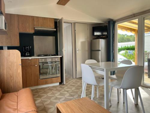 a kitchen and living room with a table and chairs at Mobil home 6/8 personnes aux Mathes / La Palmyre in Les Mathes