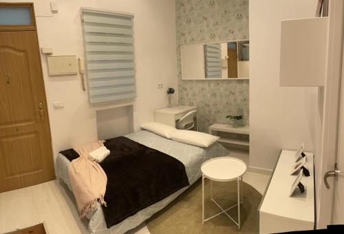 a bedroom with a bed and a table and a mirror at Encantador Puente Segovia Caramuel in Madrid