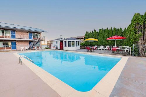 a large blue swimming pool with tables and umbrellas at Days Inn & Suites by Wyndham St. Ignace Lakefront in Saint Ignace