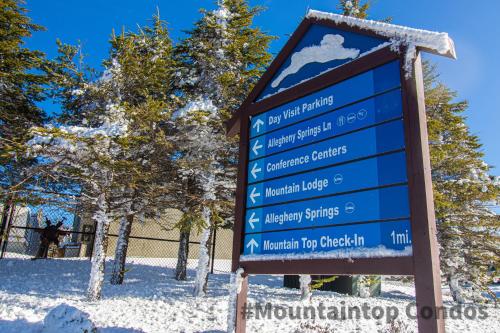 a sign in the snow next to some trees at Mountaintop Condos in Snowshoe