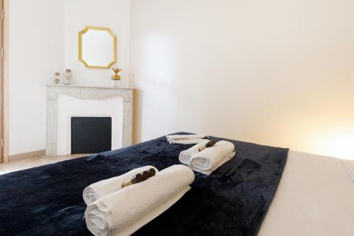 - une chambre avec 2 serviettes sur un lit et une cheminée dans l'établissement Lumière YourHostHelper, à Cannes