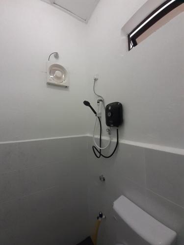 a white bathroom with a shower and a toilet at Tiny House Idaman Kuala Terengganu with Private House in Kuala Terengganu
