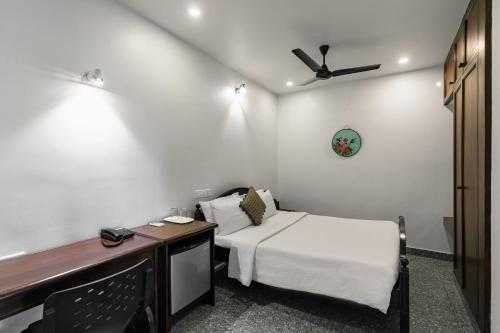 a room with a bed and a desk with a ceiling fan at Pondicherry Executive Inn in Puducherry