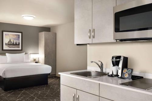 a hotel room with a bed and a kitchen at Microtel Inn & Suites Dorval QC in Dorval
