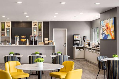 a waiting room with tables and yellow chairs at Microtel Inn & Suites Dorval QC in Dorval