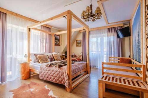 1 dormitorio con cama con dosel y banco en Willa Klimek Jacuzzi&Sauna, en Poronin
