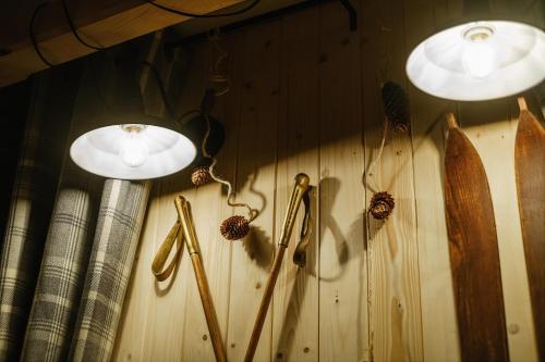three lights on a wooden wall with surfboards and sticks at WIlla JODŁA JACUZZI&SAUNA in Poronin