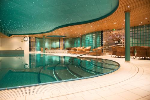 a large swimming pool in a building with a restaurant at Holmen Fjordhotell in Nesbru
