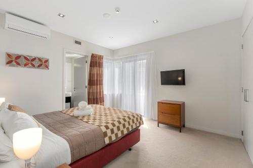 um quarto com uma cama, uma cómoda e uma televisão em The Waterfront - Paihia Holiday Apartment em Paihia