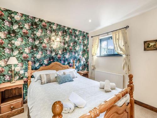 um quarto com uma cama grande e papel de parede floral em Betty Hutton - Uk36661 em Goulsby