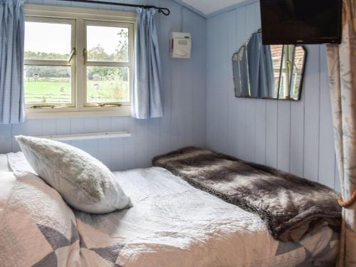 - une chambre avec un lit doté d'un oreiller et d'une fenêtre dans l'établissement Farmhouse Garden Shepherds Hut, à Thursley
