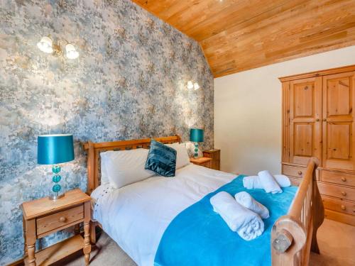 1 dormitorio con cama azul y pared de madera en Viking Cottage - Uk36662, en Goulsby