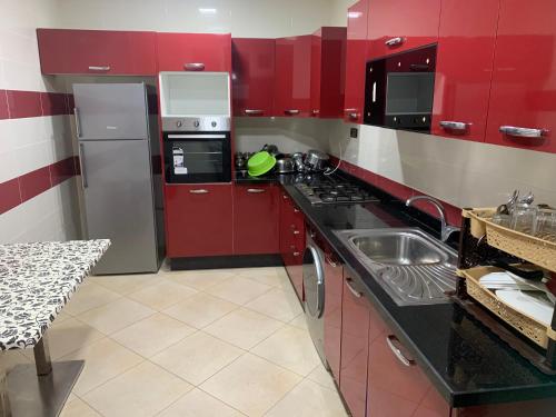 a red kitchen with a sink and a stove at اقامة السعادة in Monte ʼArrouit