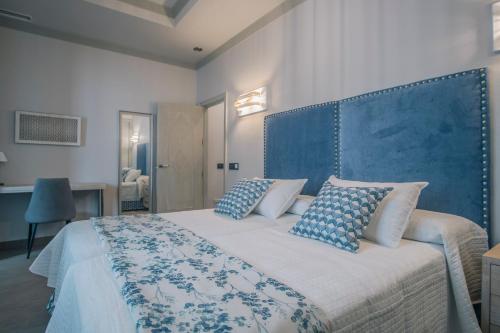 a bedroom with a bed with a blue headboard and pillows at Apartamentos Turísticos La Baílla in Rota
