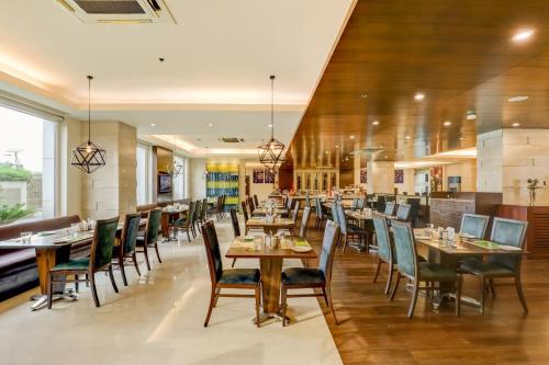 a restaurant with tables and chairs in a room at Lemon Tree Premier, Delhi Airport in New Delhi