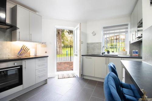 a kitchen with white cabinets and blue chairs at Station Lodge close to City Centre with parking in Exeter