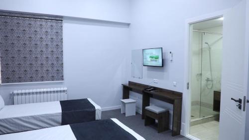 a bedroom with a bed and a desk and a shower at TASHRIF HOTEL in Qarshi