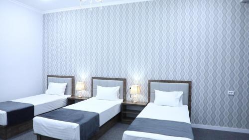 a room with two beds and two tables with lamps at TASHRIF HOTEL in Qarshi
